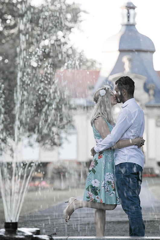 Engagementshooting Fotoshooting vor der Hochzeit in einem SChlosspark hinter einem Brunnen