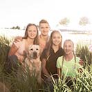 Familienbild mit Geschwistern in der Sonne draußen auf dem Feld 